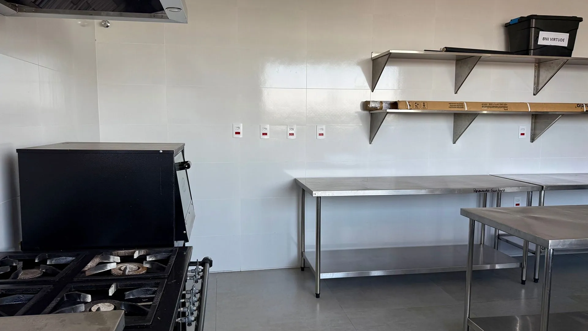 Cozinha industrial com fogão, coifa e bancadas de inox