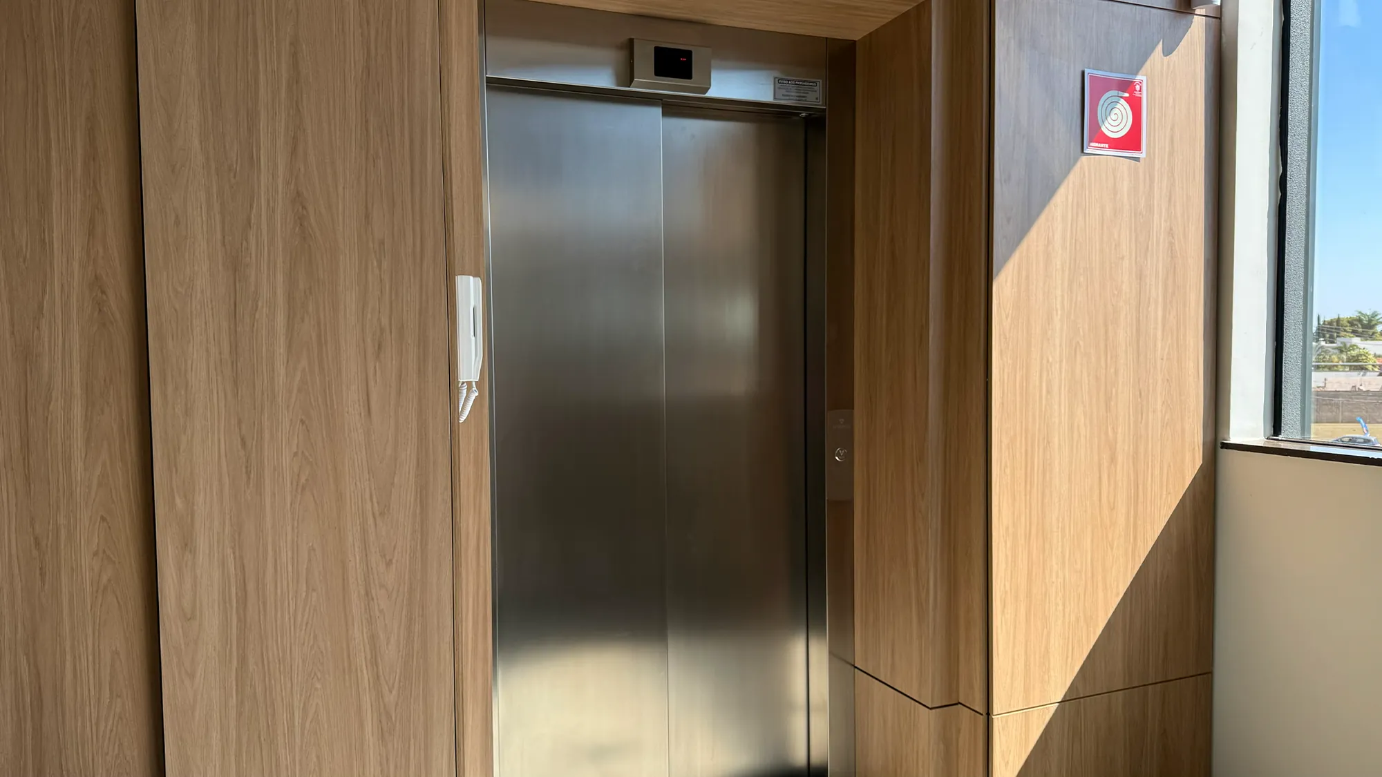 Portas de inox do elevador panorâmico, emolduradas em madeira