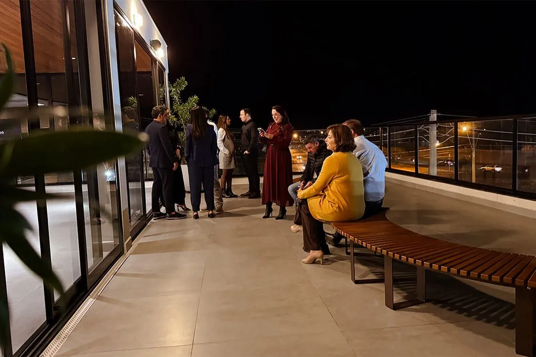 Convidados sentados nos bancos do rooftop ao anoitecer