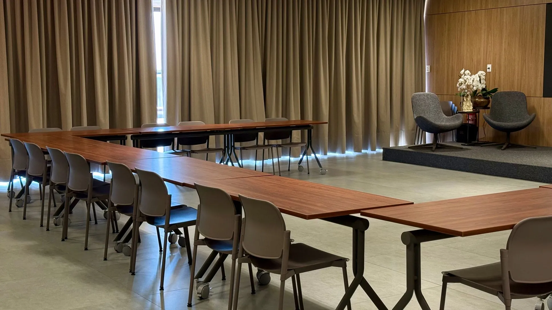 Salão montado em formato de reunião com mesas retangulares