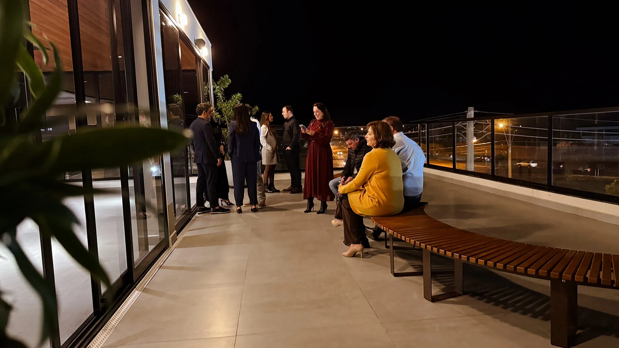 Convidados reunidos no rooftop durante evento noturno